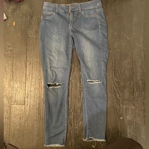 Skinny jeans with holes in knees and frayed at the bottom